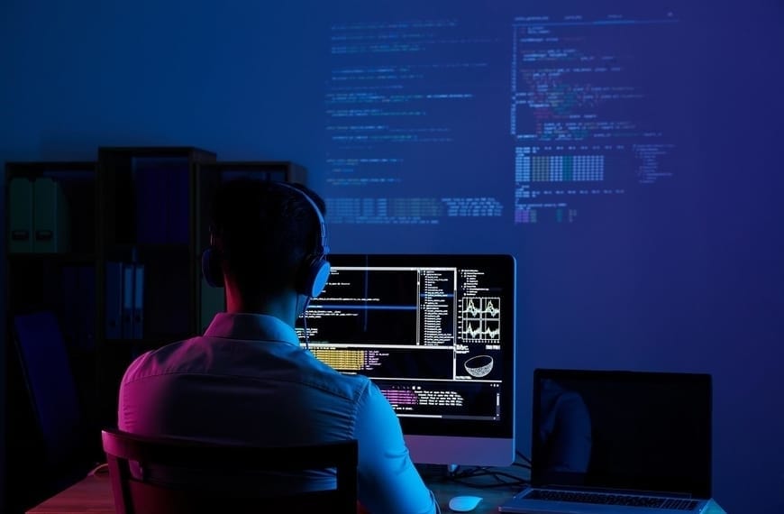 Man at a computer looking at programming code.