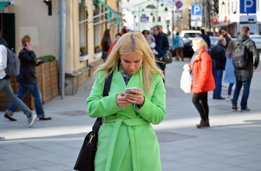 Women on a busy street looking at her cell phone.